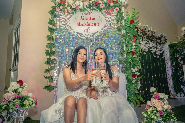 Dos mujeres sentadas con copas frente a una decoración de celebración