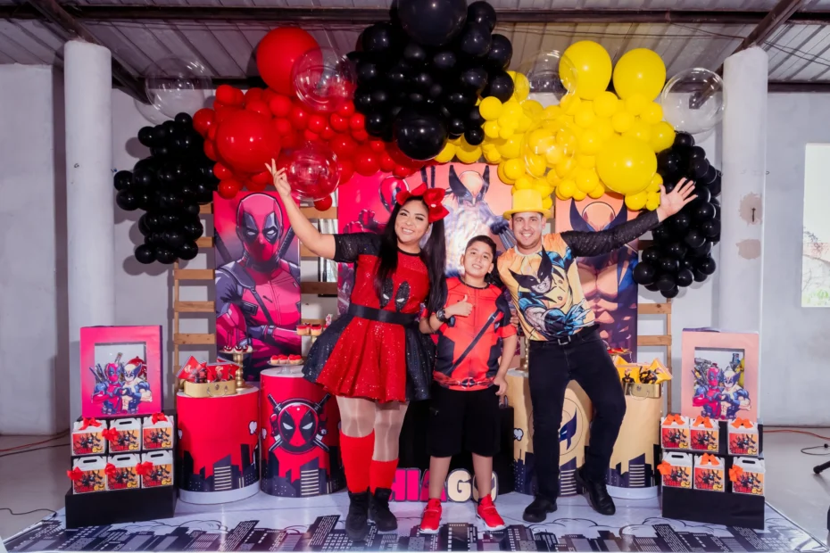 Familia frente a una decoración de cumpleaños con globos rojos, negros y amarillos