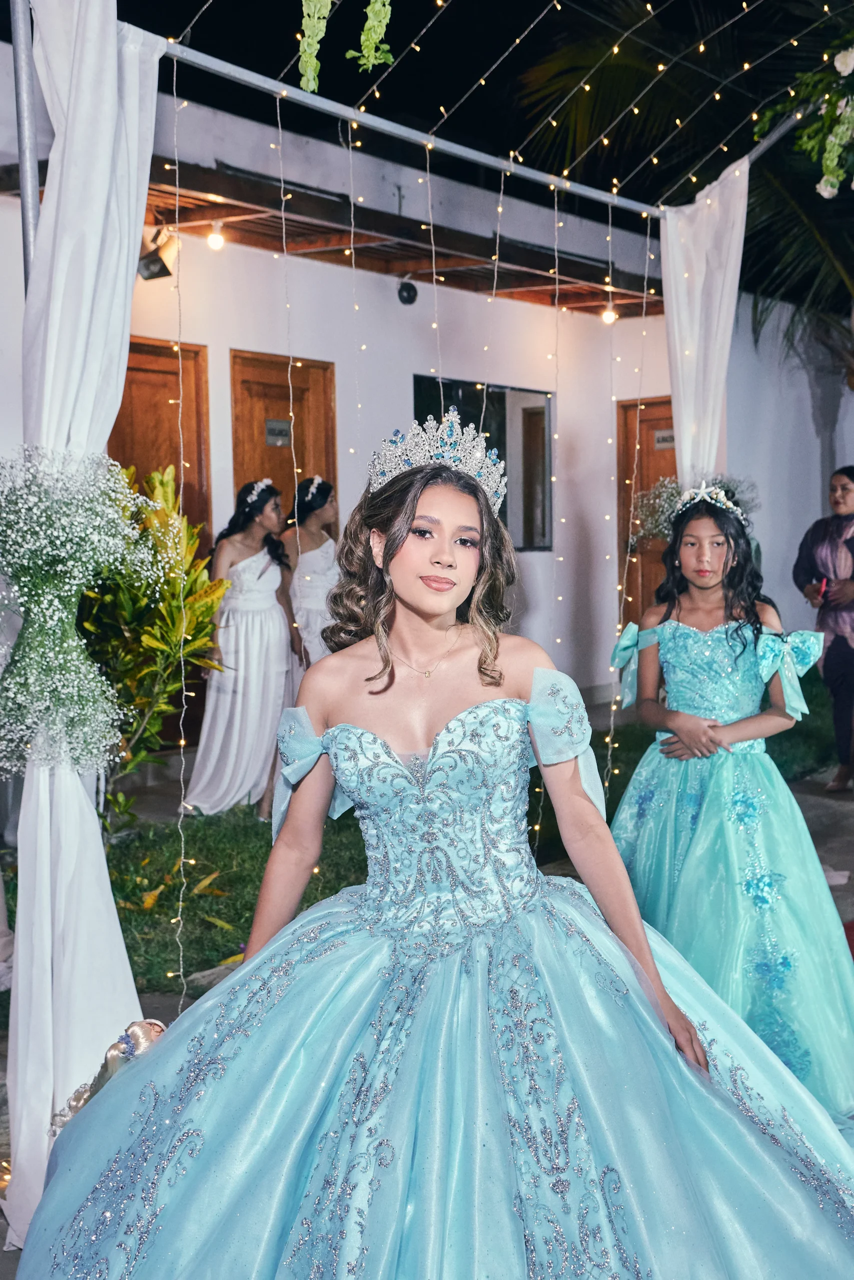 Joven con vestido verde junto a la entrada decorada de su celebración de XV